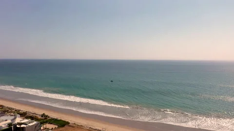 Drone flies over beach front homes in Malibu with sailboat on ocean Stock Footage 144414614