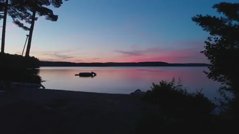 Drone flies over beach towards water trampoline during Sunset Stock Footage 168716535