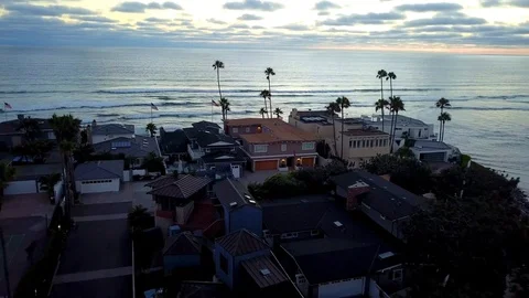 Drone flies over beachfront homes just after sunset and between palm trees 库存影片 97887719