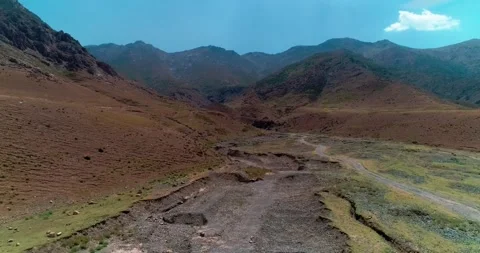 A drone flies over the bed of a dried-up river among mountains and hills Stock Footage 262948414
