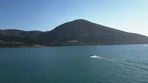 A drone flies over a blue mountain lake. A boat with tourists floats on the Stock Footage 334607293