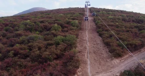 The drone flies over the cabins of the mountain cable car. At the bottom of the Stock Footage 255883259