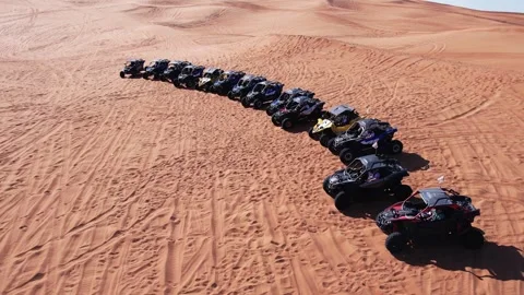 A drone flies over a caravan of buggies standing on a desert sand dune. Stock Footage 251006267