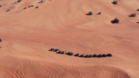 A drone flies over a caravan of buggies standing on a desert sand dune. Stock Footage 340459650
