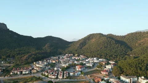 Drone flies over a city surrounded by mountains at dawn, summer day 4k Video stock 217882429