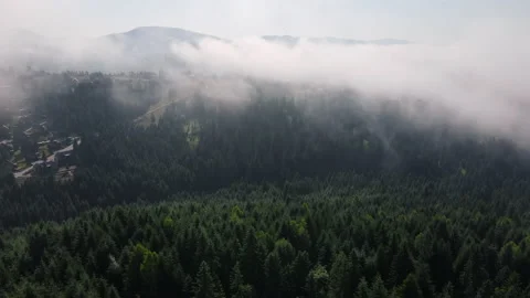 Drone flies over clouds on sunny day, houses, calm mountains and green forest Stock Footage 159677494