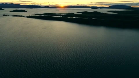 Drone flies over dark waters, dotted with islands as sun rises over mountains. Stock Footage 136001044