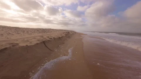 Drone flies over desert-like beach with ocean in distance Video stock 345149728