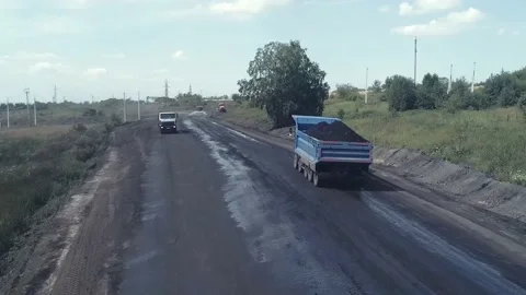 A drone flies over a dirt road behind a heavy dump truck loaded with coal Stock Footage 169590334