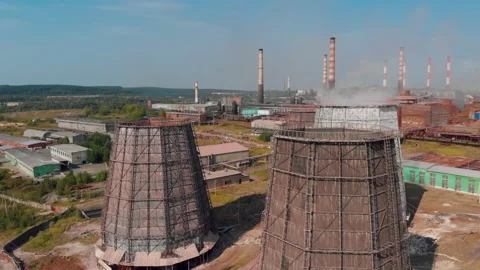 The drone flies over a factory with large chimneys of chillers from which smoke Stock Footage 165536735