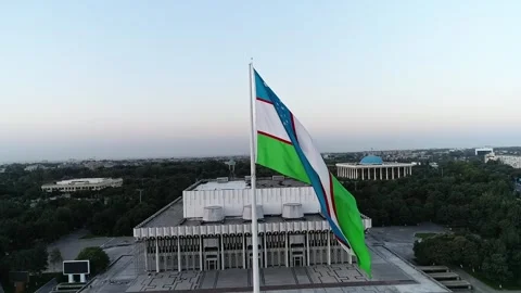 A drone flies over a giant flag in the middle of a city. Sunset sky Stock Footage 278522558