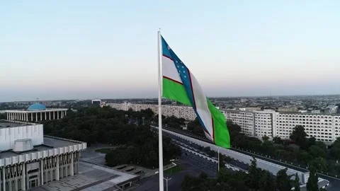 A drone flies over a giant flag in the middle of a city. Sunset sky Stock Footage 309325146