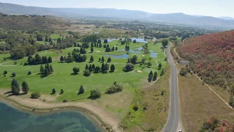 Drone flies over golf course with red trees along the mountain side because i Video stock 87191671