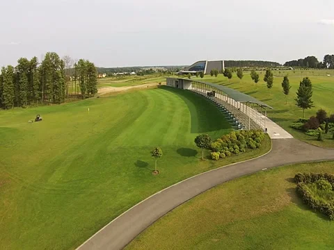 A drone flies over a green golf course with building Vídeos de archivo 79743807