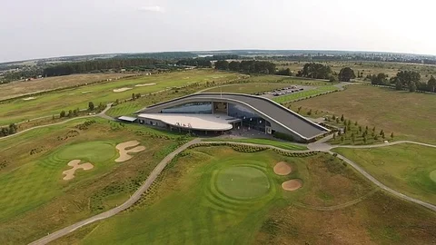A drone flies over a green golf course with golf club building Vídeos de archivo 79744655