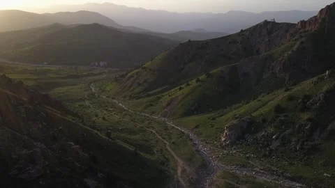 A drone flies over the green mountains illuminated by the setting sun Video stock 334606788