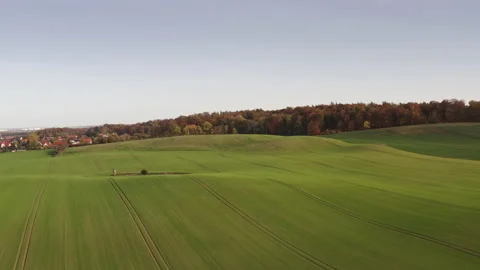 A drone flies over hilly coutryside and a forest until a river and houses can be Stock Footage 239068956