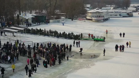 Drone flies over the hole in the winter river, people enter the cold water, Stock-Footage 222542250