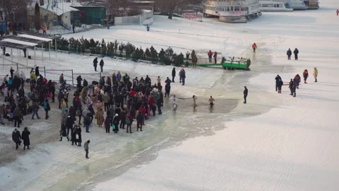 Drone flies over the hole in the winter river, people enter the cold water, Stockbeeldmateriaal 222542438