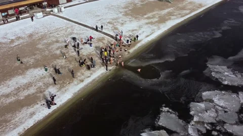 Drone flies over the hole in the winter river, people enter the cold water, Stock Footage 229846365