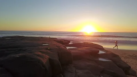Drone flies over huge boulder to reveal stunning beach at sunset Stock Footage 100867315