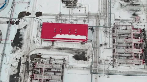 A drone flies over an industrial area in winter, pipelines and tanks in the snow Vidéo 190885025