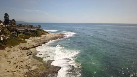 Drone flies over a mansion lined cliff with private beaches below on a sunny day Stock Footage 97164384