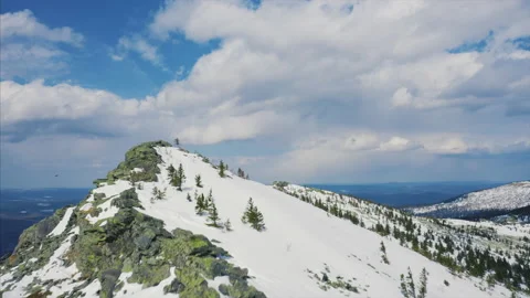 Drone flies over mountain ridge, blue cloudy sky and snow covered slopes Stock Footage 166114866