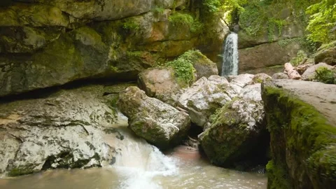 A drone flies over a mountain river through huge rocks to a waterfall Video stock 201180807
