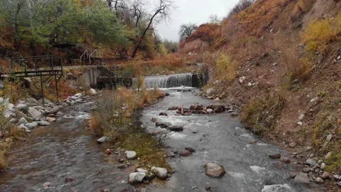 Drone flies over mountain river, water cascades down. Mountain river in autumn Stock Footage 226595300