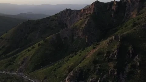 A drone flies over mountains covered with greenery on a sunny spring day Stock Footage 334606388