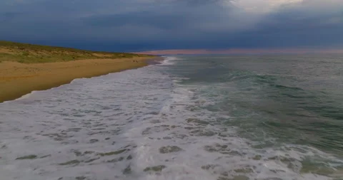 A drone flies over the ocean's breaking wave at sunset Stock Footage 254359038