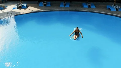 Drone flies over a pool in Egypt, where a woman swims on a mattress Stock Footage 129077619