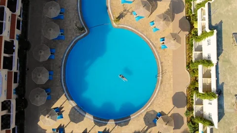 Drone flies over a pool in Egypt, where a woman swims on a mattress 스톡 동영상 129095014
