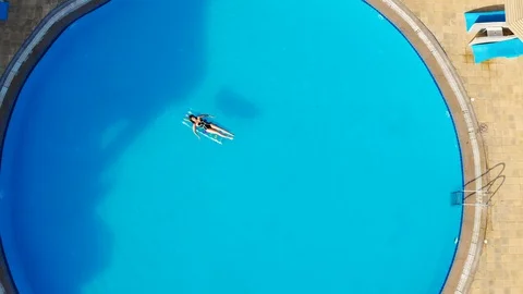 Drone flies over a pool in Egypt, where a woman swims on a mattress Stock Footage 129232959