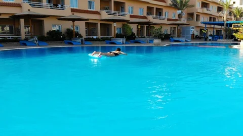 Drone flies over a pool in Egypt, where a woman swims on a mattress Stock Footage 129265769