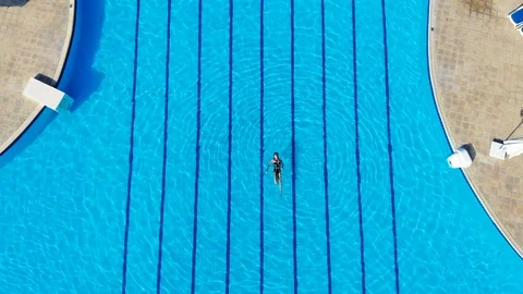 Drone flies over a pool in Egypt, where a woman swims on a mattress Stock Footage 129272819