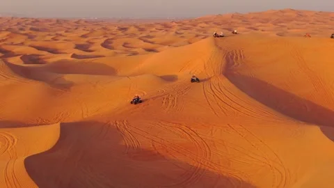A drone flies over quad bikes driving through the sand dunes of the desert in Stock Footage 250451474