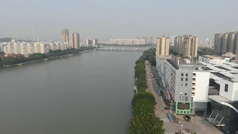 A drone flies over a river along which a road passes along which cars drive. Stock Footage 113801564