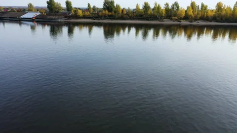 Drone flies over the river approaching the shore. Autumn forest on the shore is Stock Footage 142923377