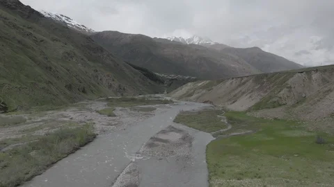 Drone flies over river with flow in mountains. Aerial view of Kazbegi, Georgia. Video stock 123561476