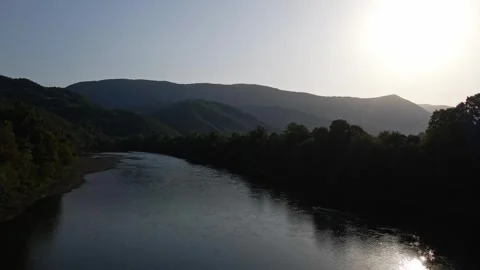 Drone flies over river in a valley of wooded mountains in sunset Stock Footage 263060003