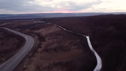 Drone flies over the road and hills at sunset Stock Footage 174299502