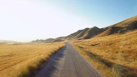 Drone flies over road between fields.Raw footage included with the color graded  Stock Footage 90985821