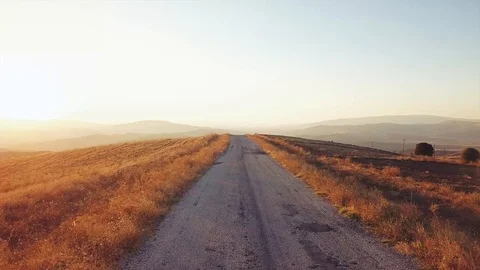 Drone flies over road between fields.Raw footage included with the color graded  Video stock 90985908