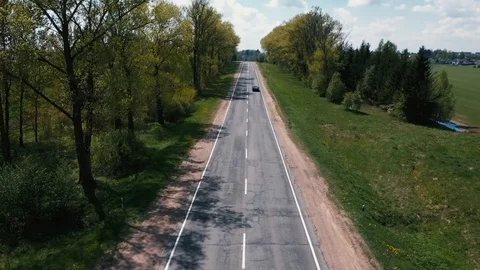 The drone flies over the road between the trees and watching the cars Vídeos de archivo 107926934