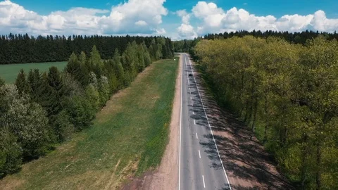 The drone flies over the road between the trees and watching the cars Stock Footage 107927019