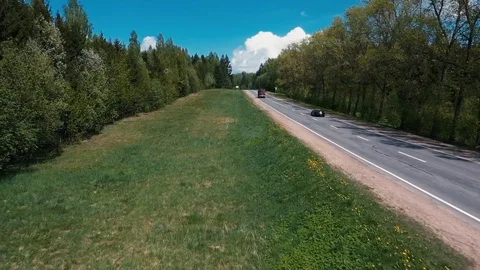 The drone flies over the road between the trees and watching the cars Vidéo 107927566