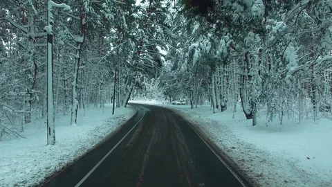Drone flies over the road through the winter snow forest . Car POV. Stock Footage 83747298