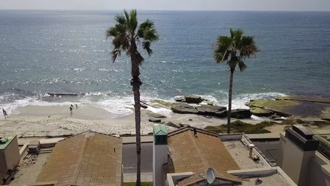 Drone flies over row of beachfront homes and palm trees in San Diego Stock Footage 97973384